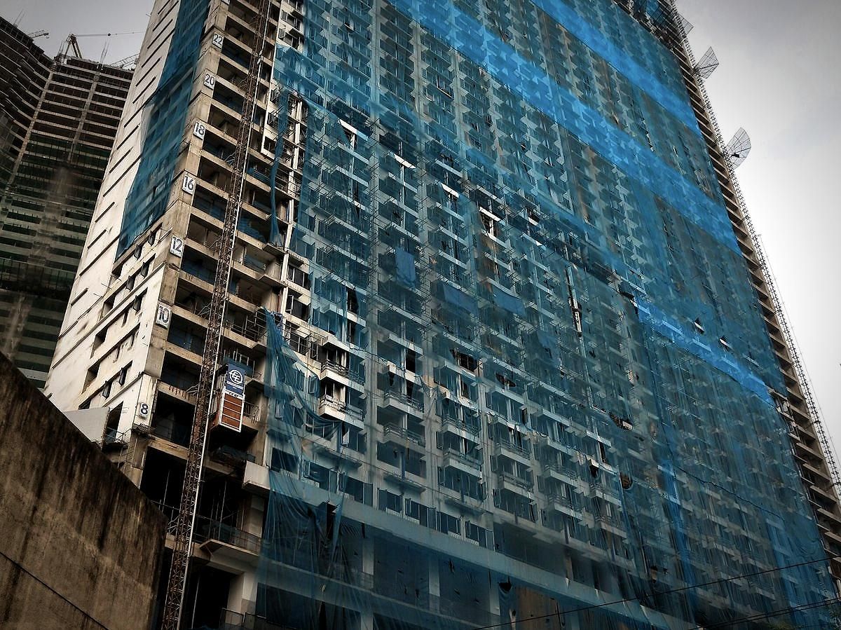 High rise building under construction wrapped in safety netting