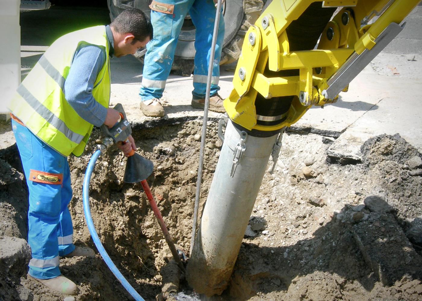 Vacuum excavation of a utility trench beside a hi vis worker