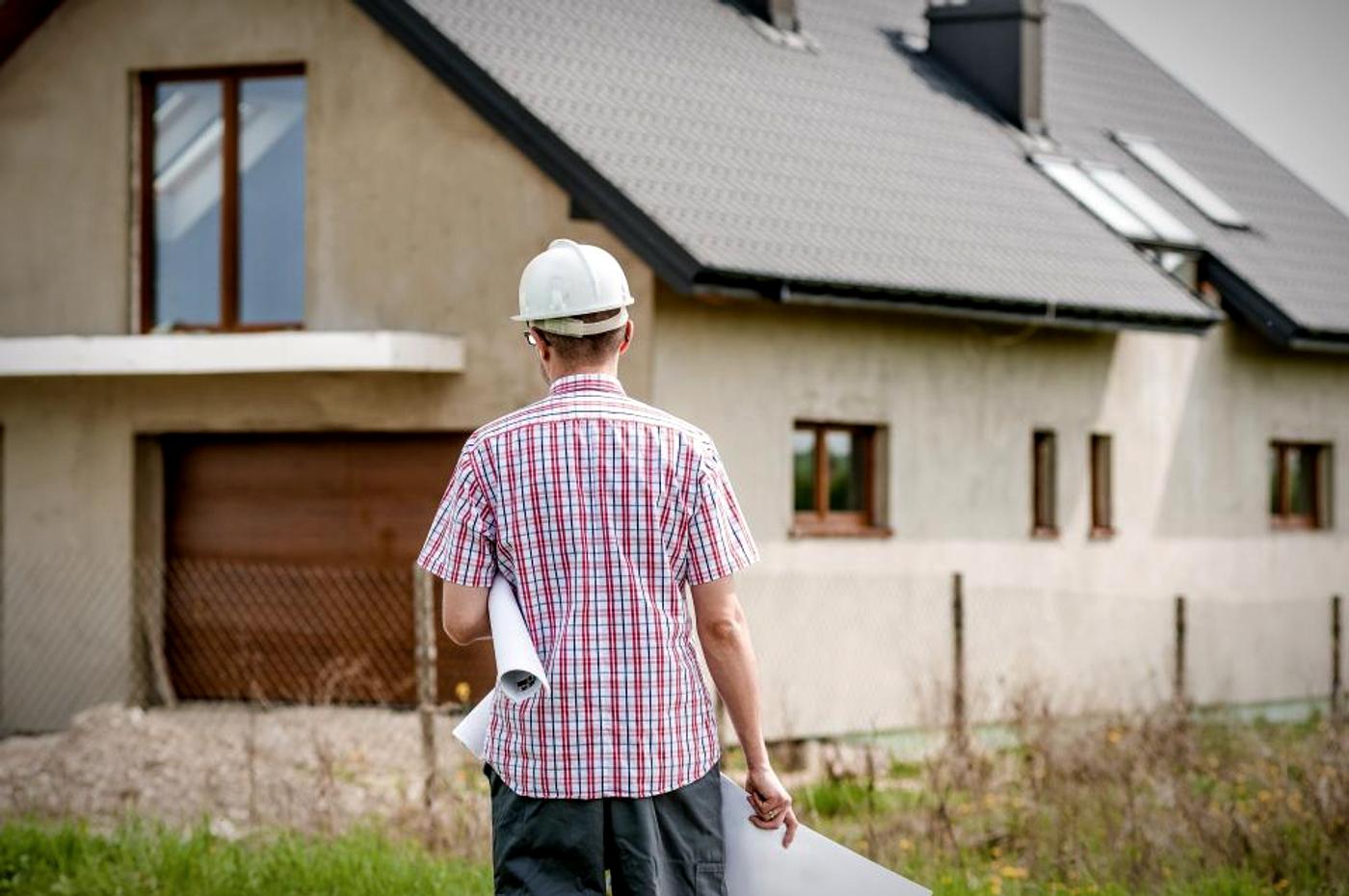 Site manager in a hard hat reviewing rolled plans on a jobsite