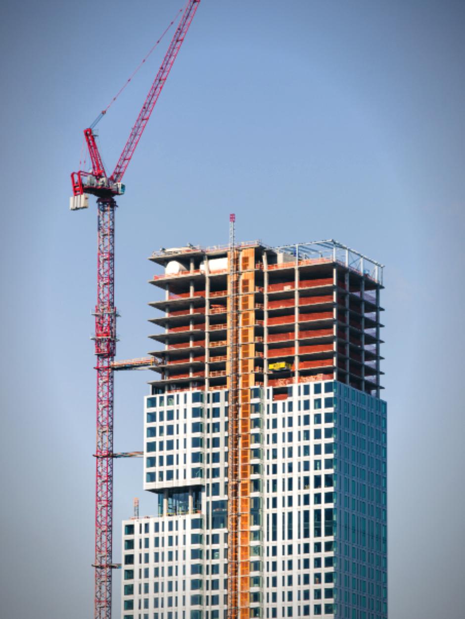 Glass high rise tower topping out with a tower crane